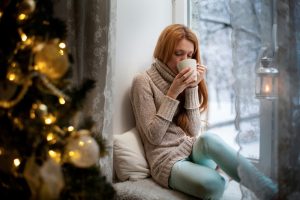 woman sipping hot drink in the wintertime, indoors