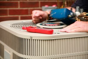 technicians-hands-with-tools-on-top-of-outdoor-ac-unit