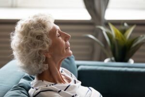 senior-woman-leaning-back-on-sofa-breathing-deeply